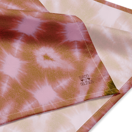 Band of Muses Cinnamon Bandana, featuring a tie-dye patterned fabric with pink and a maroon Band of Muses logo in the corner